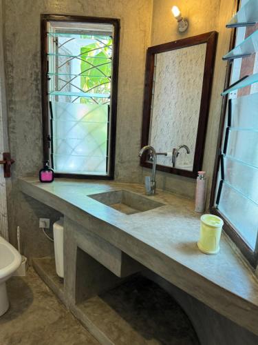 a bathroom with a sink and a mirror and a toilet at Coastal calm apartment in Watamu