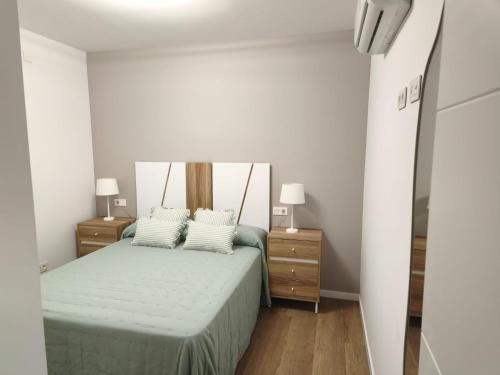 a bedroom with a bed with two night stands and two lamps at Casa O OLIVO in Boiro