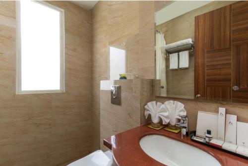 a bathroom with a sink and a mirror at OPO Horizon LYRO Hotel , Formerly known as Inde Hotel in Gurgaon