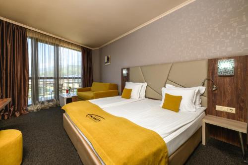 a hotel room with a large bed with a yellow blanket at SPA Hotel Infinity Park Velingrad in Velingrad