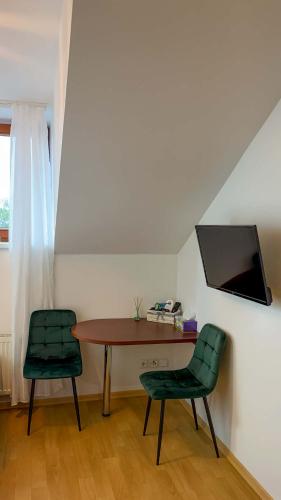 a room with a table and two green chairs at Penzion Navara in Kolín