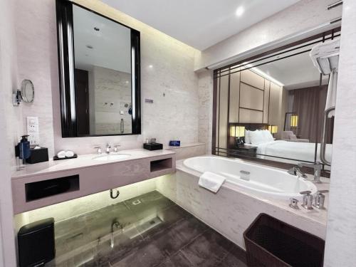 a bathroom with a tub and a sink and a bed at Radisson Blu Resort Wetland Park in Wuxi