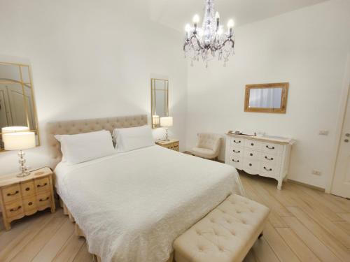 a white bedroom with a large bed and a chandelier at Palazzo Spasiano rooms - SORRENTO CENTER in Sorrento