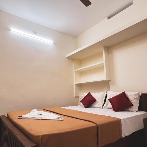 a bedroom with a bed with red and white pillows at AMAN Residency in Kallar Vattiyar