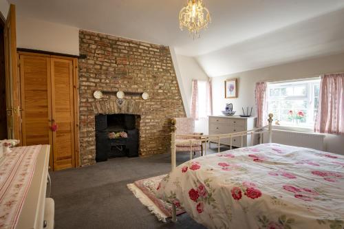 a bedroom with a bed and a brick fireplace at Lyke Wake Cottage in Northallerton