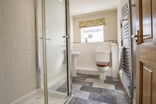 a bathroom with a shower and a toilet and a sink at Lyke Wake Cottage in Northallerton