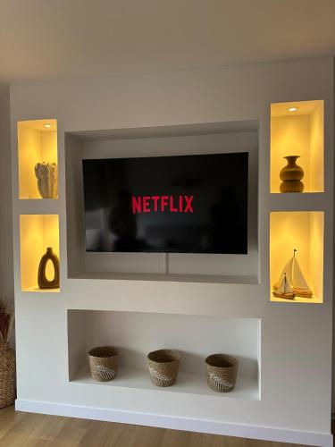 a flat screen tv on a wall with baskets at Le Cocon de Milan in Valras-Plage