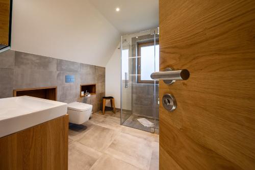 a bathroom with a toilet and a glass shower door at Neue Büdnerei in Althagen