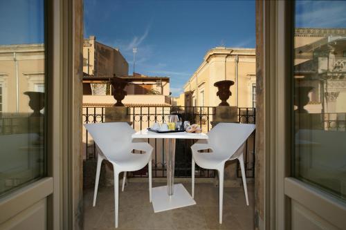 a white table and chairs on a balcony at Hotel Porta Reale in Noto