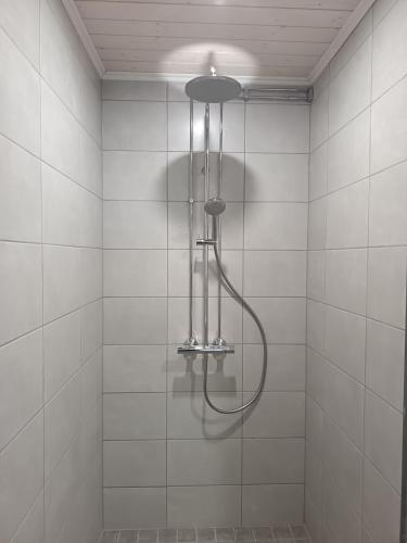a shower in a white tiled bathroom at Venetsianranta in Saarijärvi
