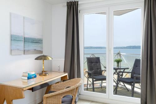 a room with a desk and chairs and a view of the ocean at Strandhotel Laboe Nr 35 in Laboe