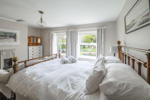 a white bed in a bedroom with a window at Mollies Cottage in Overstrand