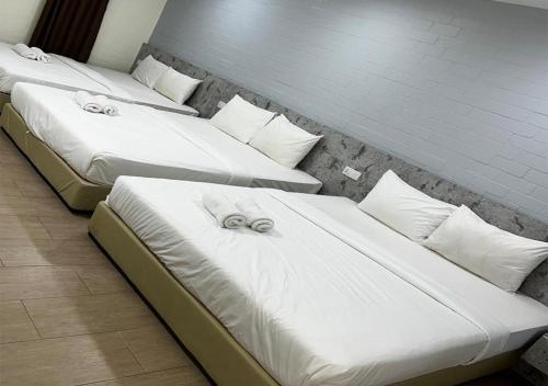 a row of three beds in a room at D'Lima Beach Inn in Pantai Cenang