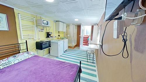 a small room with a purple bed and a kitchen at Apartaments Segur Kandy 1 in Calafell