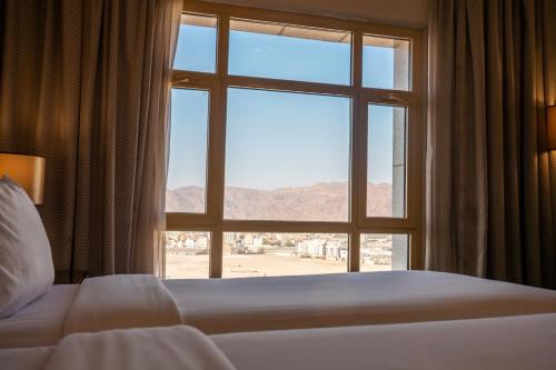 a bedroom with a large window with a view of the desert at SAJA By Warwick Madinah Hotel in Medina