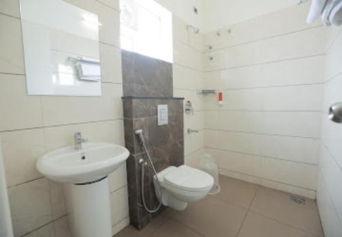 a white bathroom with a toilet and a sink at Nandha Grande in Udumalaippettai