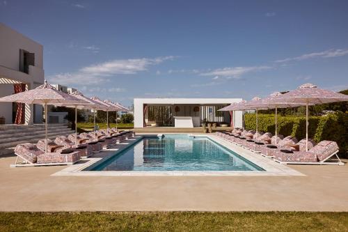 a swimming pool with chairs and umbrellas at Tzanis Resort Skyros in Skiros