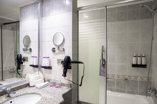 a bathroom with a shower and a sink and a phone at SAJA By Warwick Madinah Hotel in Medina