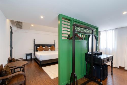 a green room with a bed and a room with a desk at Bangluang Boutique Hotel nearby Wat Arun in Bangkok