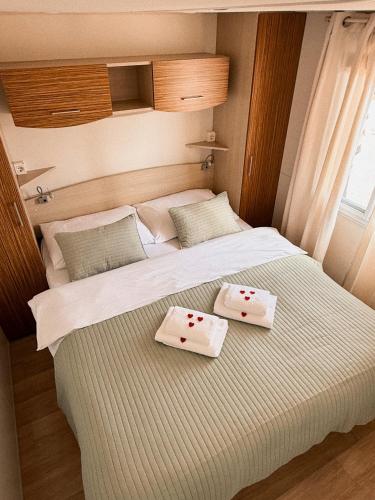 a bedroom with a large bed with two plates on it at Auto-kamp Dvije suze 1 in Brištane