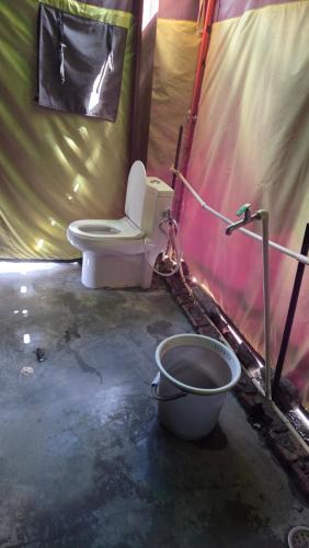 a bathroom with a toilet and a bucket at Lord Shiva Camps in Sari