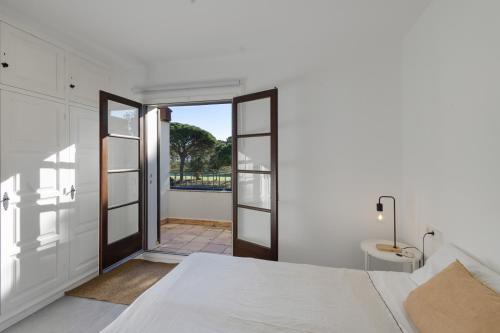 a white bedroom with a door leading to a balcony at Racó 24 in Pals