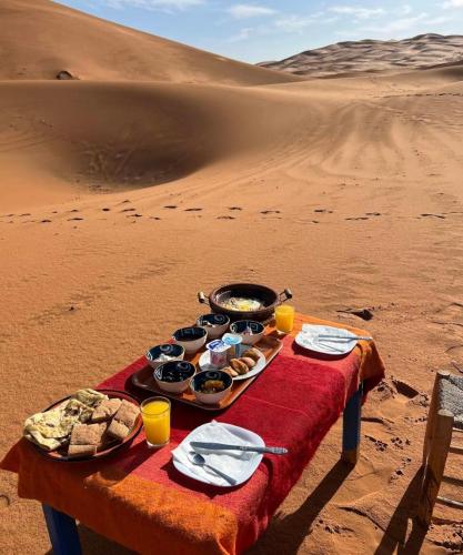 a table with food on it in the desert at Erg Chebbi Nomad Camp in Merzouga