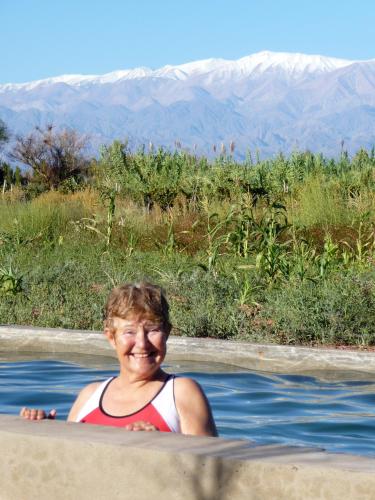 a woman in a hot tub with mountains in the background at Chakana Hospedaje Rural in Villa Unión