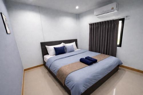 a bedroom with a large bed with blue pillows at Damiya Peaceful House in Ban Bo Dan
