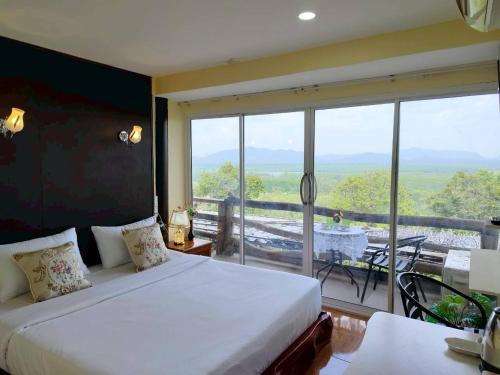 a bedroom with a bed and a large window at BaanPhutawanLanta resort & cafe in Ko Lanta