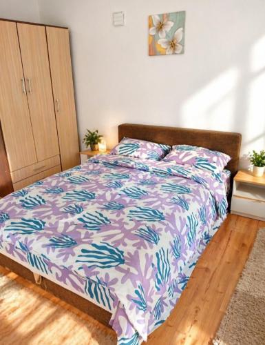 a bedroom with a bed with a purple and blue comforter at Stan na dan ,, Vidovdan ,, in Nevesinje