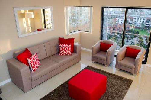 a living room with a couch and two chairs at Knightsbridge Luxury Apartments in Cape Town