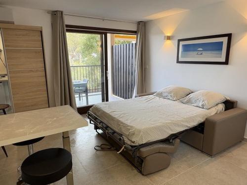 a bedroom with a bed and a table and a balcony at Superbe studio terrasse piscine et plage in Fréjus
