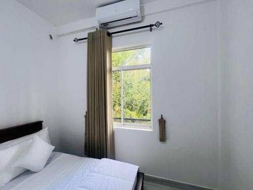 a bedroom with a bed and a window at Emerald Leaf Kandy Villa in Panabokka