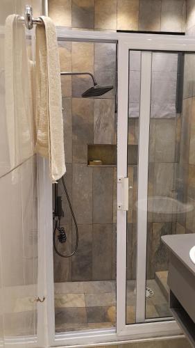 a shower with a glass door in a bathroom at Cheers Guesthouse in Botianaw