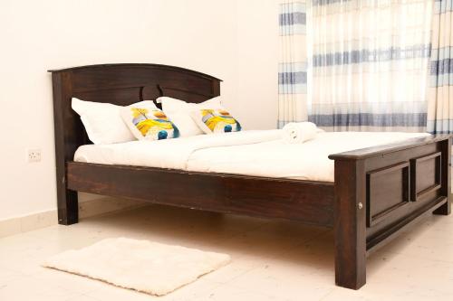 a wooden bed with white sheets and pillows at Eldoville Home in Eldoret