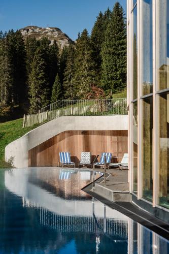 a group of chairs sitting next to a swimming pool at Hotel Goldener Berg in Lech am Arlberg