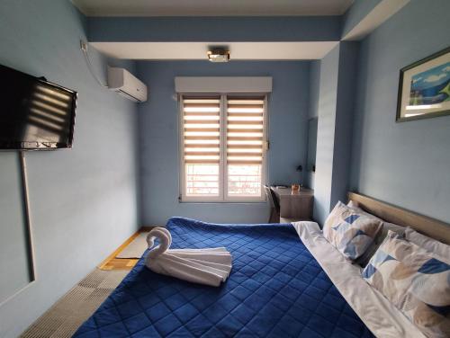 a bedroom with a bed with a blue comforter and a window at Apartment Temple in Podgorica