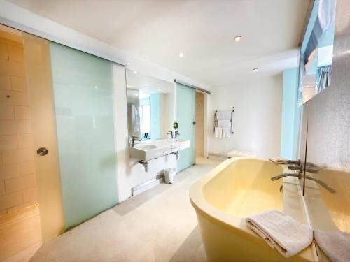 a large bathroom with a tub and a sink at Citrus Hotel Cheltenham by Compass Hospitality in Cheltenham