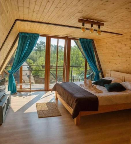 a bedroom with a large bed with blue curtains at Poienița Lupului in Vărbilău
