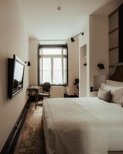 a bedroom with a bed and a desk and a window at AlmaLusa Baixa/Chiado in Lisbon