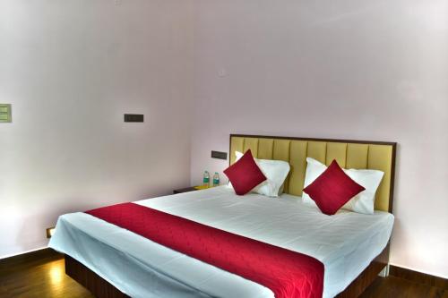 a bedroom with a large bed with red pillows at Bio Villas Resorts in Yelagiri