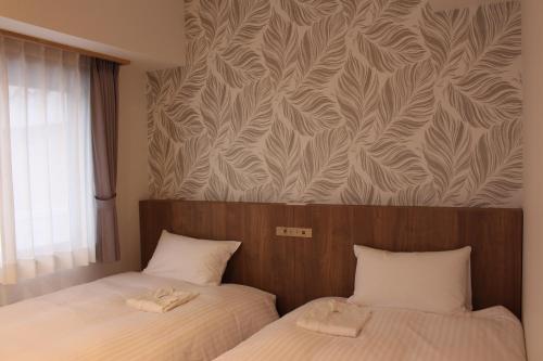 a bedroom with two beds and a wall with a pattern at Art Five Hotel BOIS博多 in Fukuoka