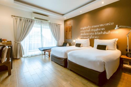 a hotel room with two beds and a window at Brown House Hotel in Udon Thani