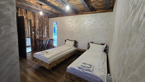 two beds in a room with wooden walls at La Hotar in Buchin