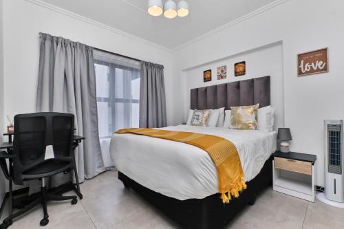 a bedroom with a bed and a desk and a chair at Chanty Serenity- workstation, gym, backup power &Pool in Sandton