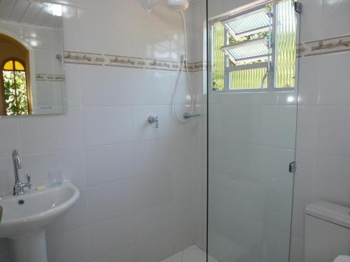 uma casa de banho branca com um chuveiro e um lavatório. em Aratinga Inn em Abraão
