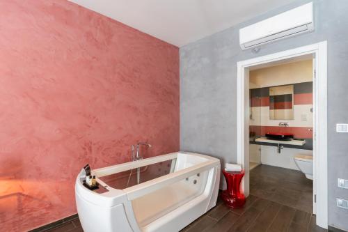 a bathroom with a tub and a pink wall at Quaint Boutique Hotel Sannat in Sannat