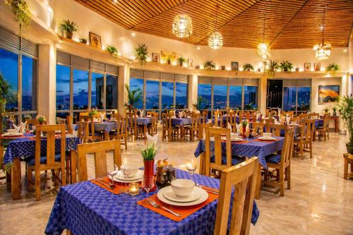 a restaurant with blue tables and chairs and windows at Kaliba Beach - Rutsiro in Rutsiro