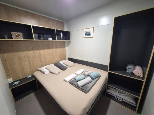 a small room with a bed with towels and shelves at SUNNY Rest Nest in Pakoštane